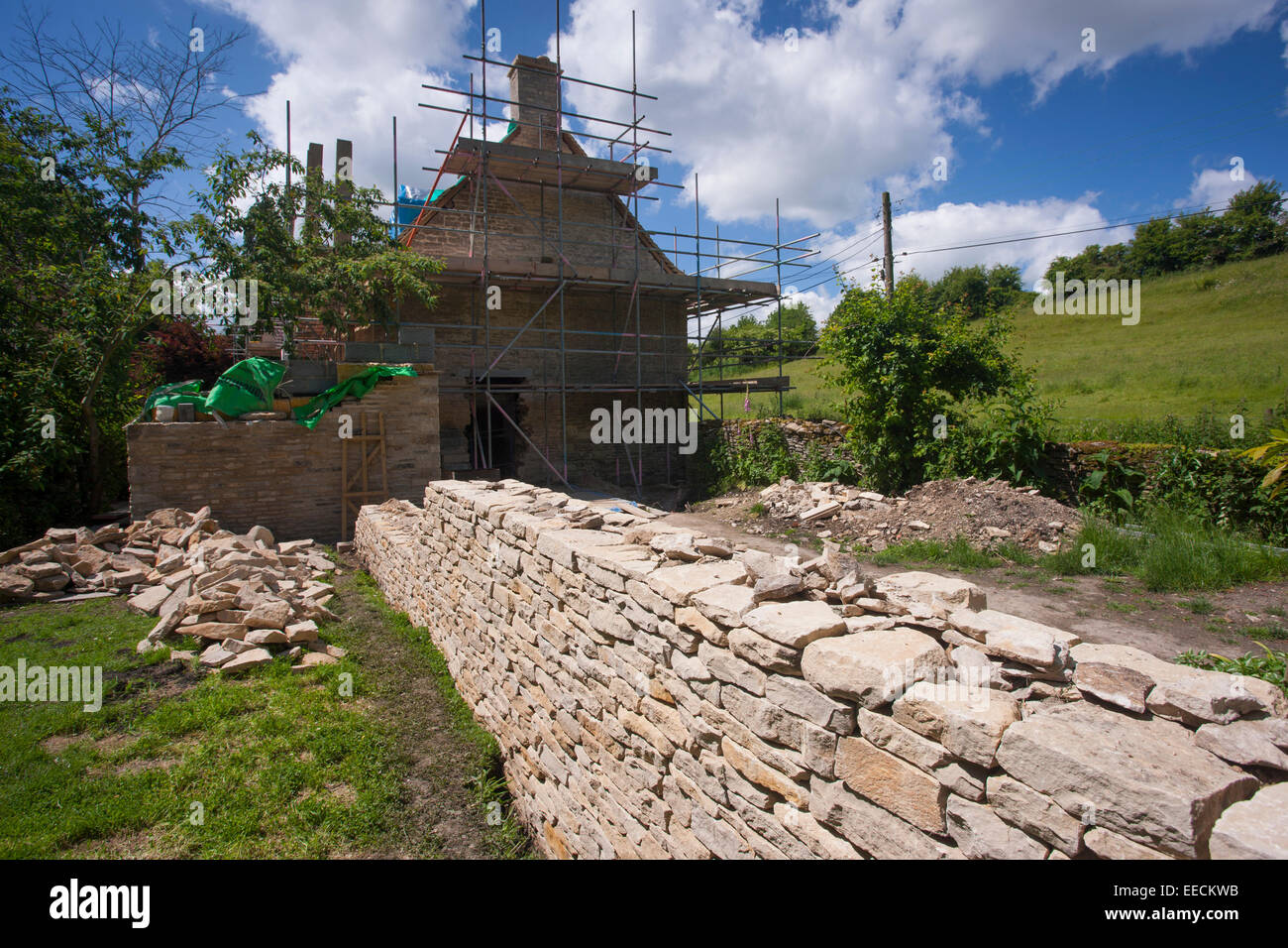 Renovation and new built dry stone wall constructed of new Cotswolds stone using traditional method at period property, UK Stock Photo