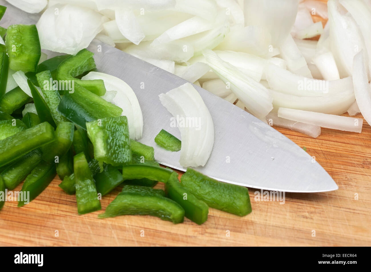 Diced green bell pepper and sweet onion with chef knife on wood cutting ...