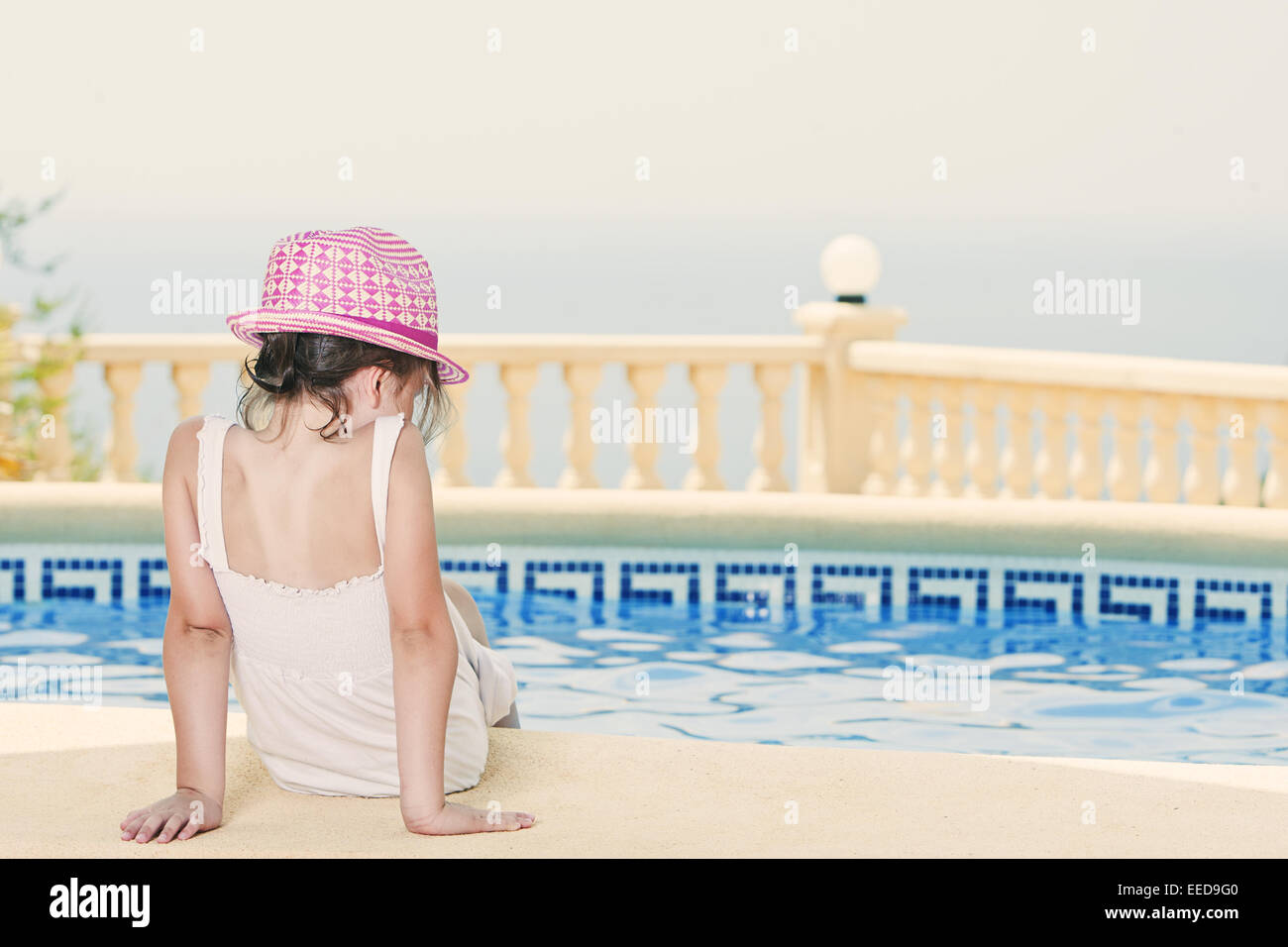 Shot of a Young Girl Sitting by the Pool Stock Photo