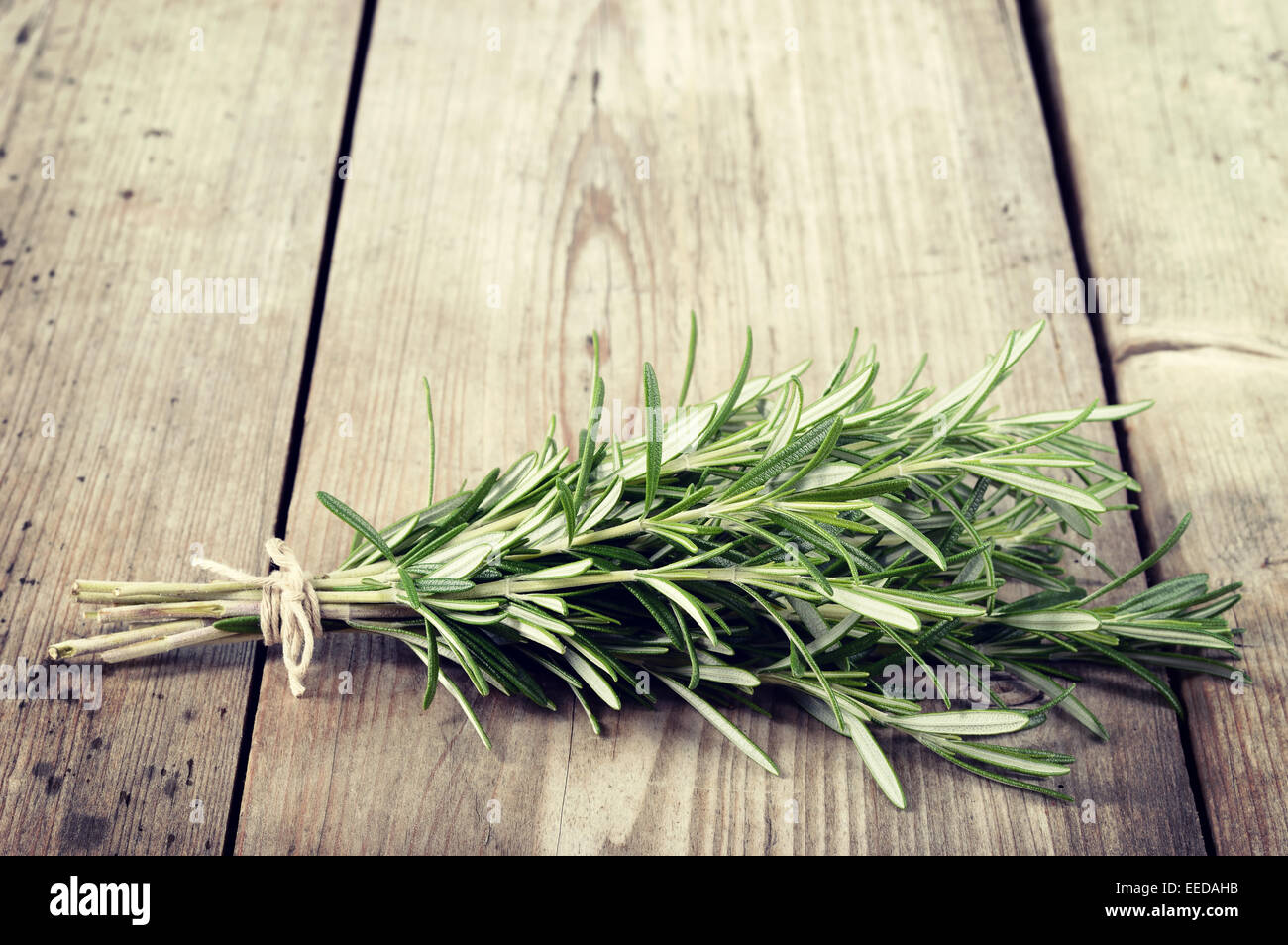 Fresh bunch of rosemary on wooden table. Aromatic evergreen herb, many culinary and medicinal uses. Rosmarinus officinalis. Stock Photo