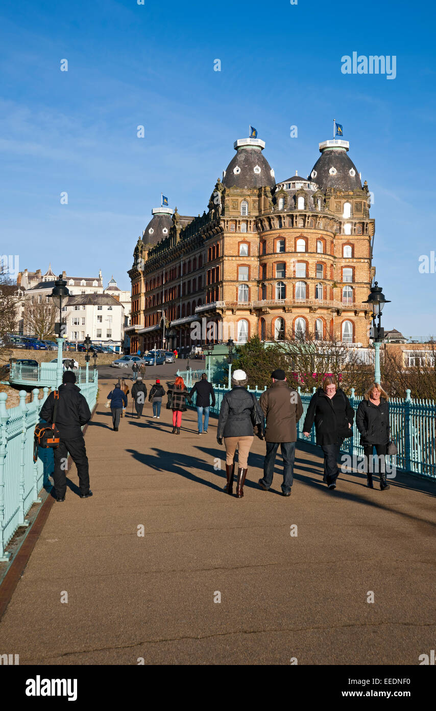 People tourists visitors walking across the Spa Bridge and The Grand Hotel in winter Scarborough North Yorkshire England UK United Kingdom Britain Stock Photo