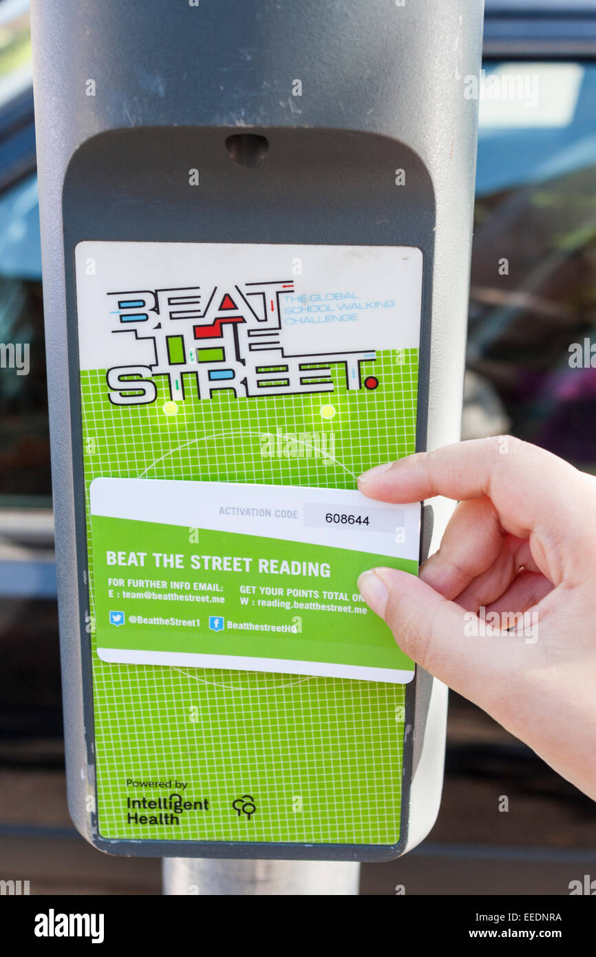 A child's hand taps a card onto a 'Beat the Street' box on a lampost to register distance walked. Stock Photo