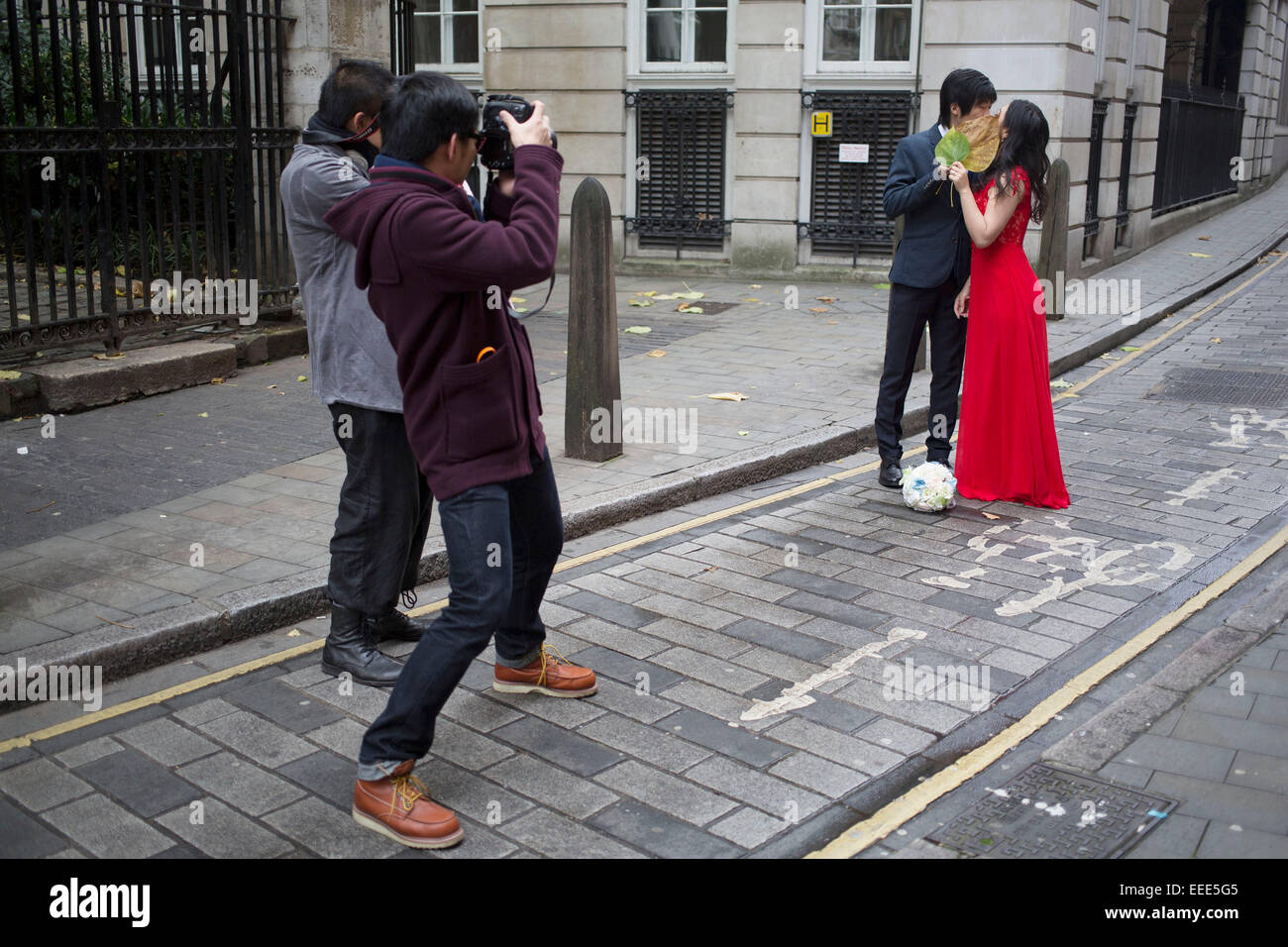 Asian photographer photographing a Chinese couple for their wedding pictures. London, UK. This is a common sight as couples from Asia have their photographs done as before their actual wedding day wearing their dress and suit. Stock Photo