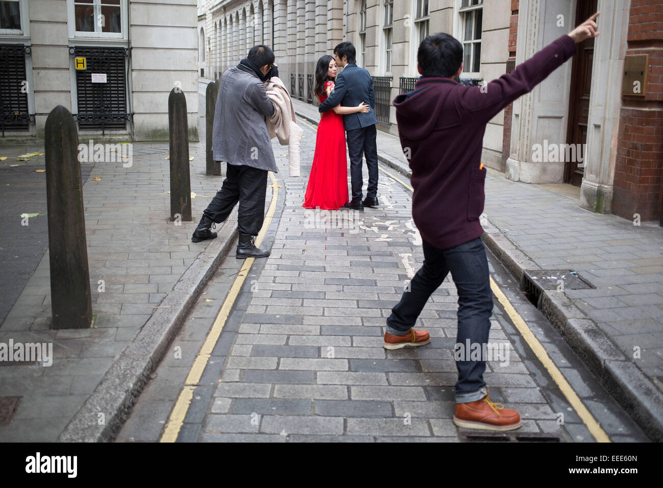 Asian photographer photographing a Chinese couple for their wedding pictures. London, UK. This is a common sight as couples from Asia have their photographs done as before their actual wedding day wearing their dress and suit. Stock Photo