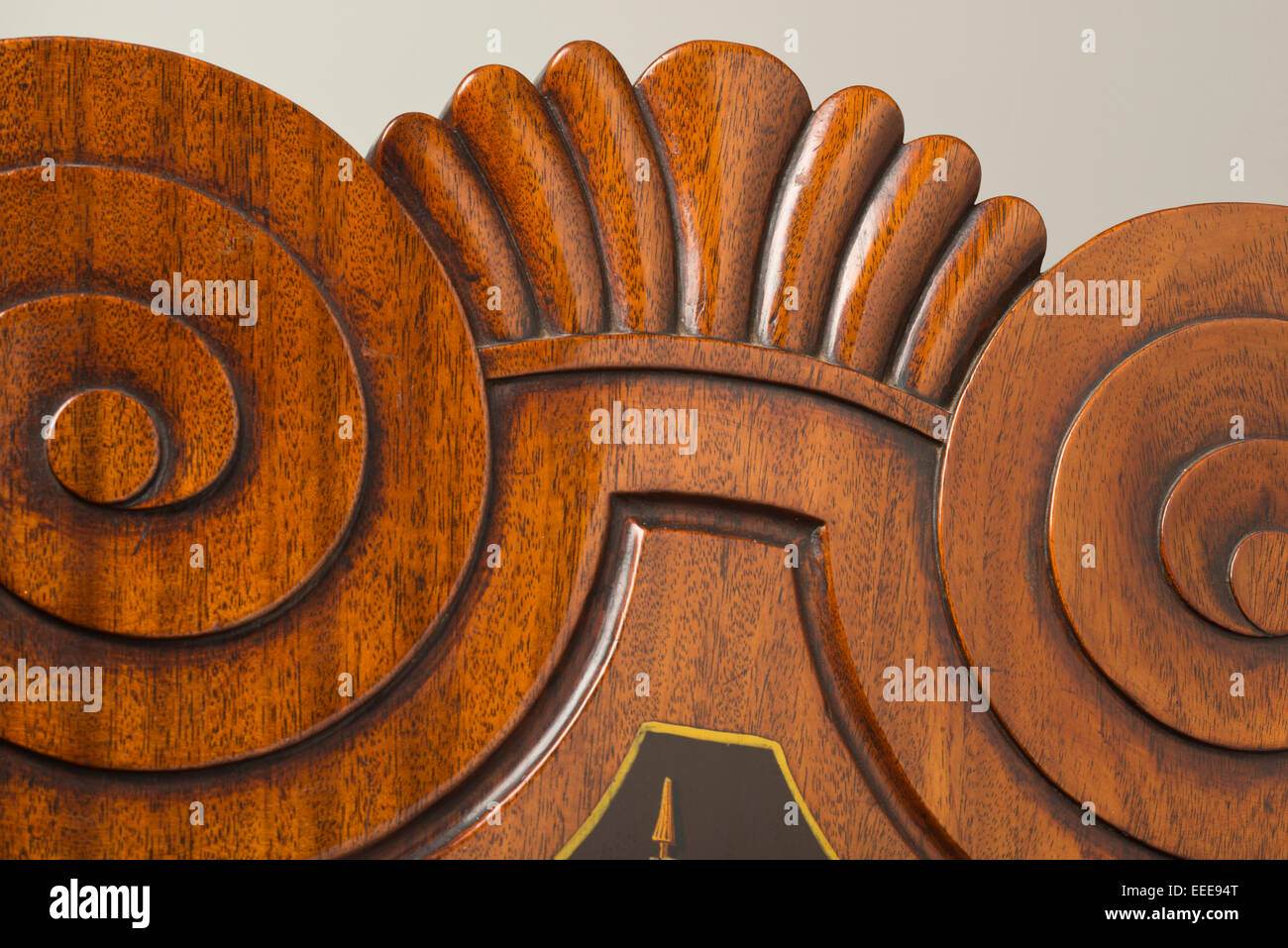 Curled swirl or spiral motifs carved into mahogany antique wooden chair with scalloped top. Stock Photo
