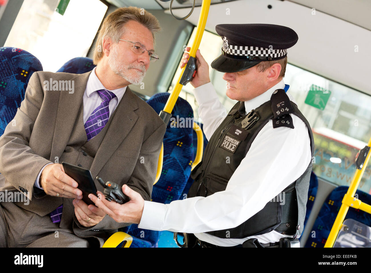 Police officer checking identification on a London Bus Stock Photo