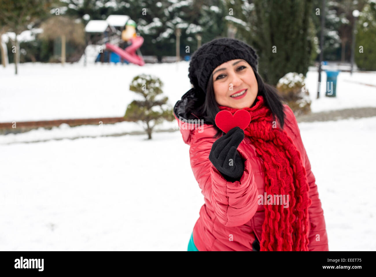 Black haired Turkish women holding a red heart in her hand.Valentine's day with snowy background Stock Photo