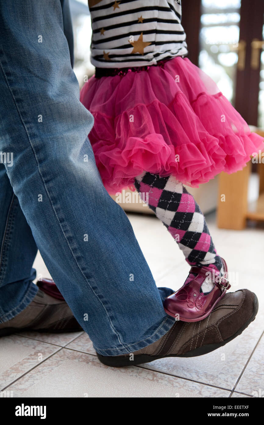Little girl standing on her father's dancing feet. Stock Photo