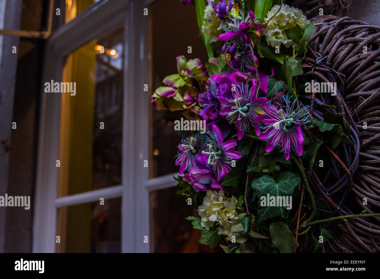 Flowers in a wicker basket hanging on a wall outside of a shop in