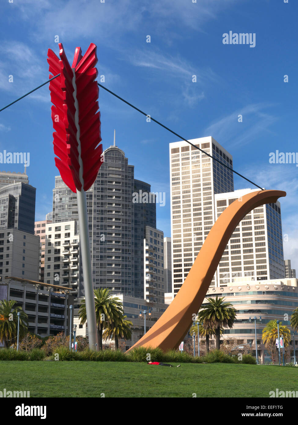 'Cupid's Span' a giant bow and arrow sculpture on the Embarcadero with man lying on grass San Francisco California USA Stock Photo