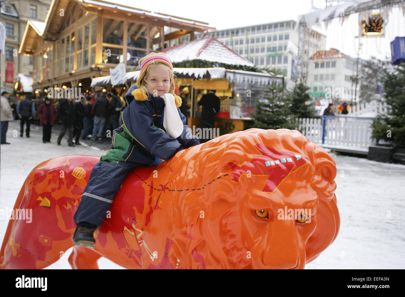 Deutschland Muenchen München Kind Maedchen reiten Loewe Plastik aussen Bayern Adventszeit Weihnachtszeit Weihnachtsmarkt Weihnac Stock Photo