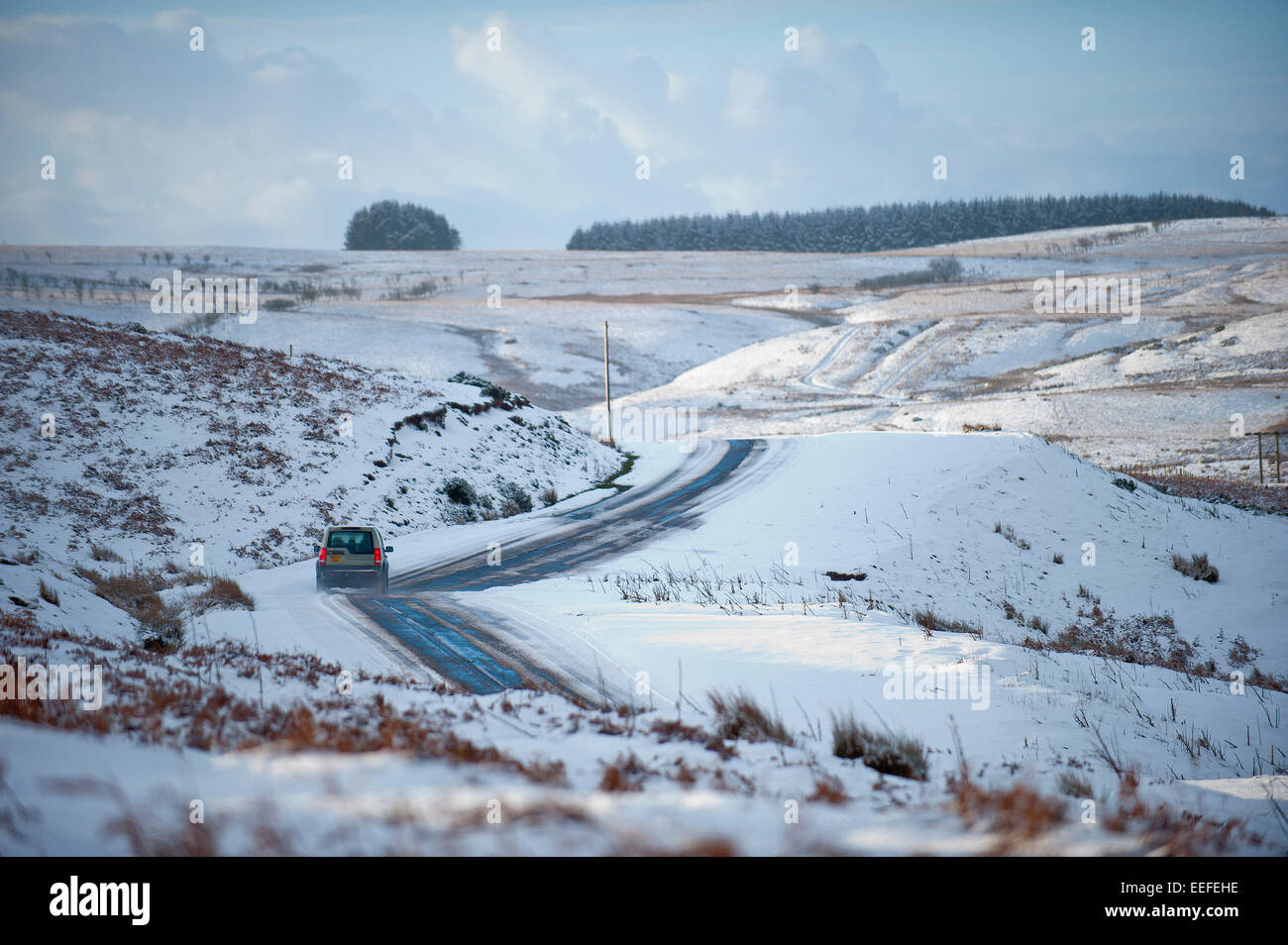 Mynydd Epynt, Powys, UK. 17th January, 2015. A motorist drives through a winter landscape along the A4520 'Brecon Road' over the moorland between Brecon and Builth Wells. There was an overnight snowfall on high land in Mid-Wales. Credit:  Graham M. Lawrence/Alamy Live News. Stock Photo