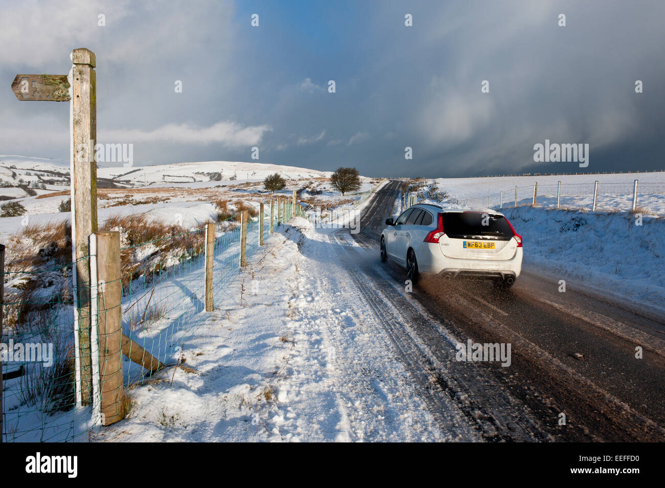 Mynydd Epynt, Powys, UK. 17th January, 2015. A motorist drives through a winter landscape along the B4520 'Brecon Road' over the moorland between Brecon and Builth Wells. There was an overnight snowfall on high land in Mid-Wales. Credit:  Graham M. Lawrence/Alamy Live News. Stock Photo