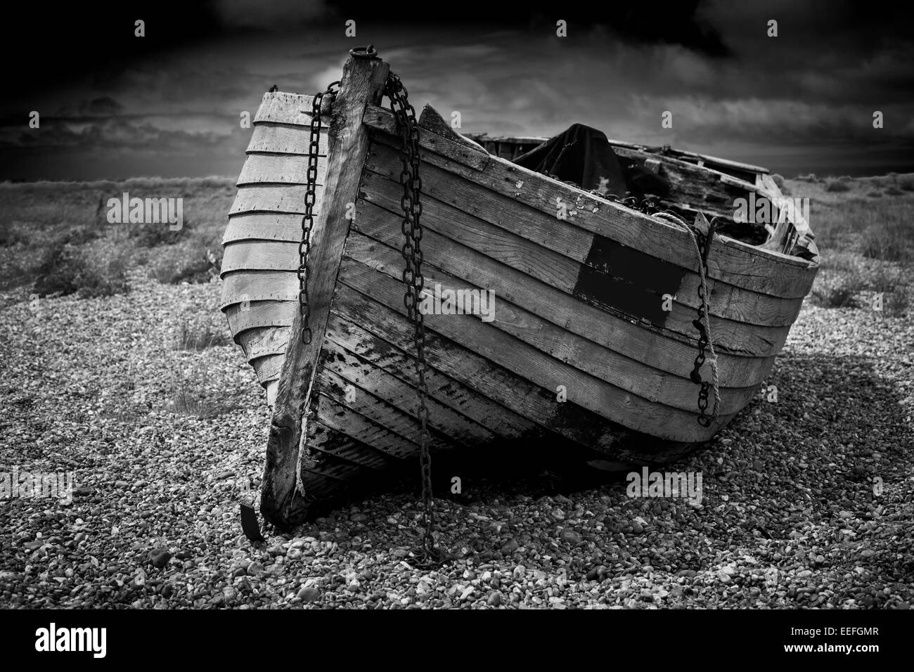 An old abandoned fishing boat stranded on a beech in black and white ...