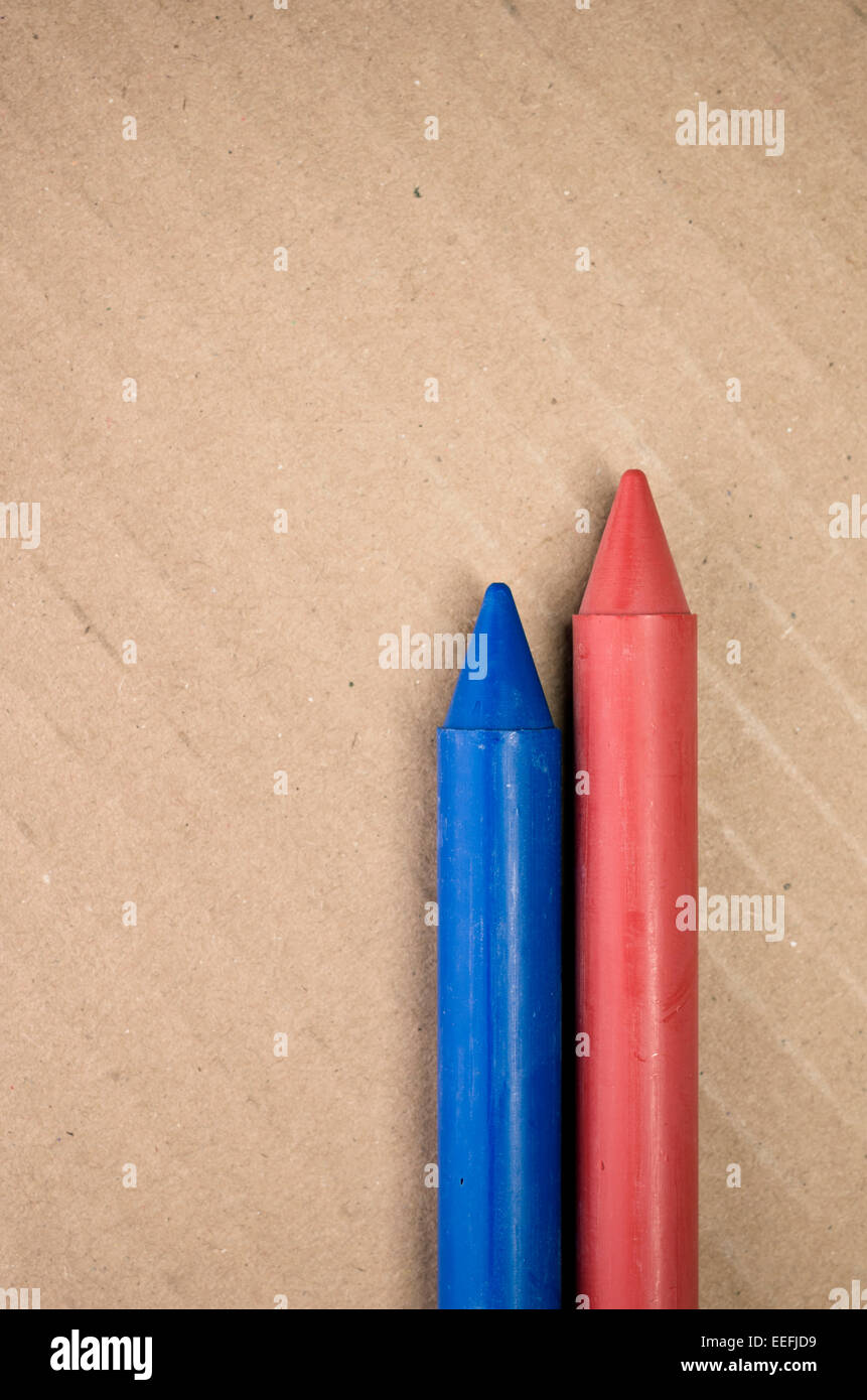 red blue colored crayons close up on a blurred light paperboard ...