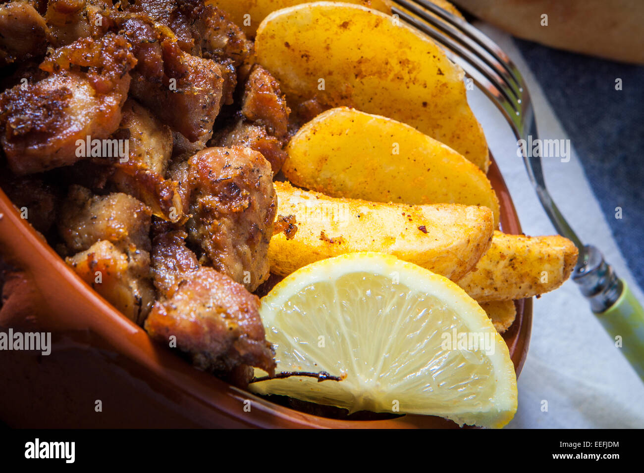 deep fried pork meat with fries and lemon served in clay pot Stock Photo