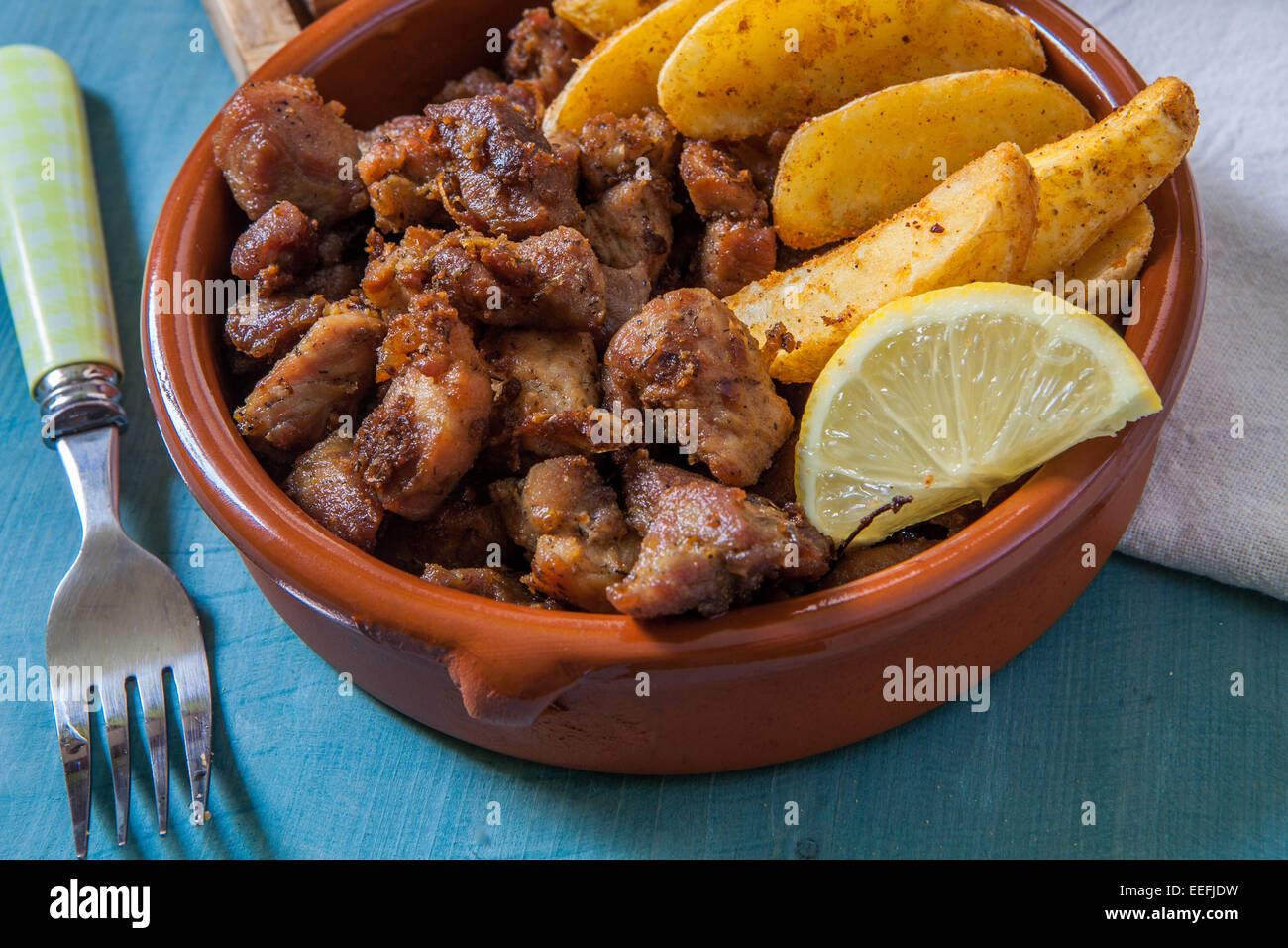 deep fried pork meat with fries and lemon served in clay pot Stock Photo
