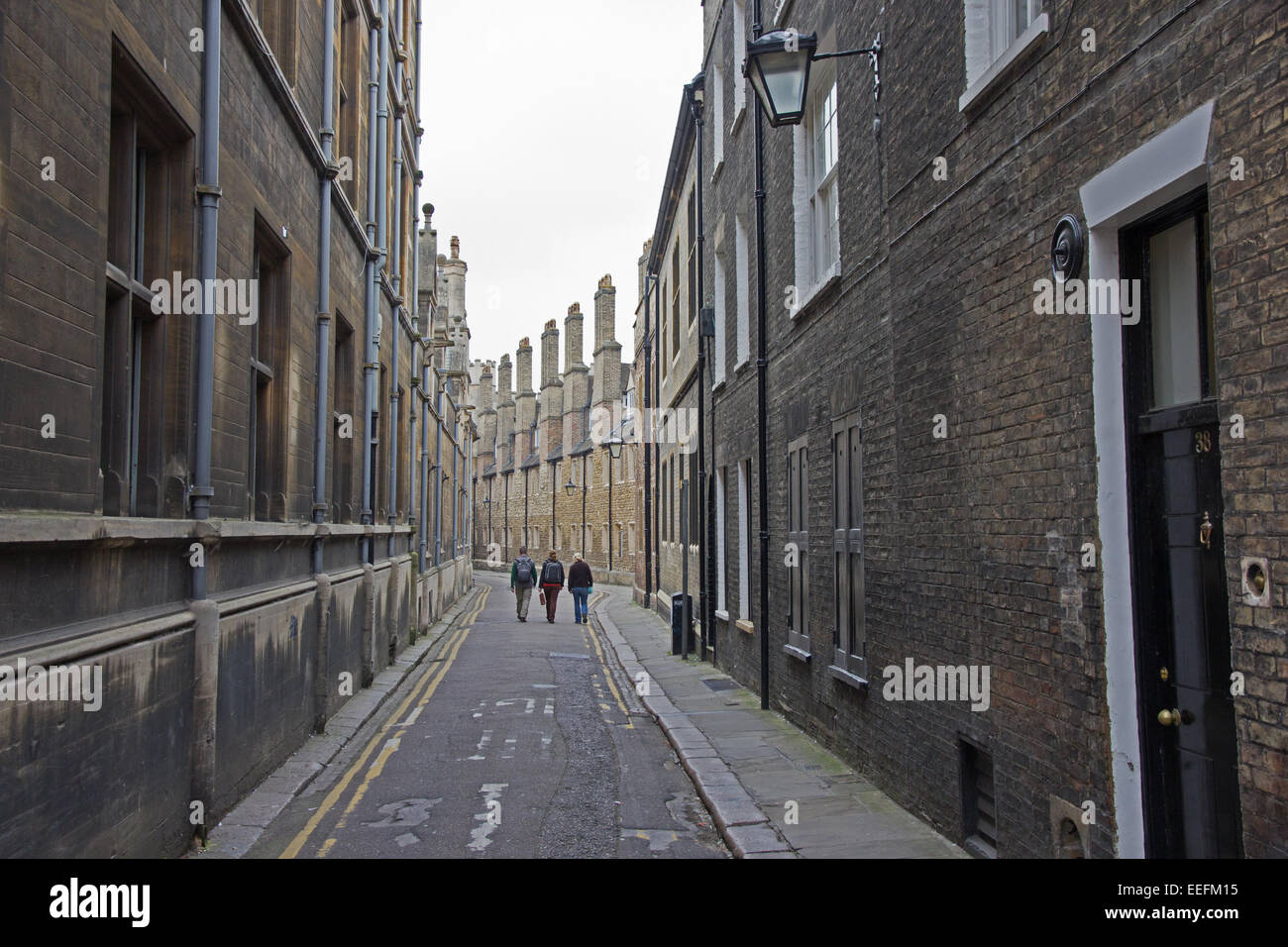 Three young people walk down back street of Cambridge Stock Photo