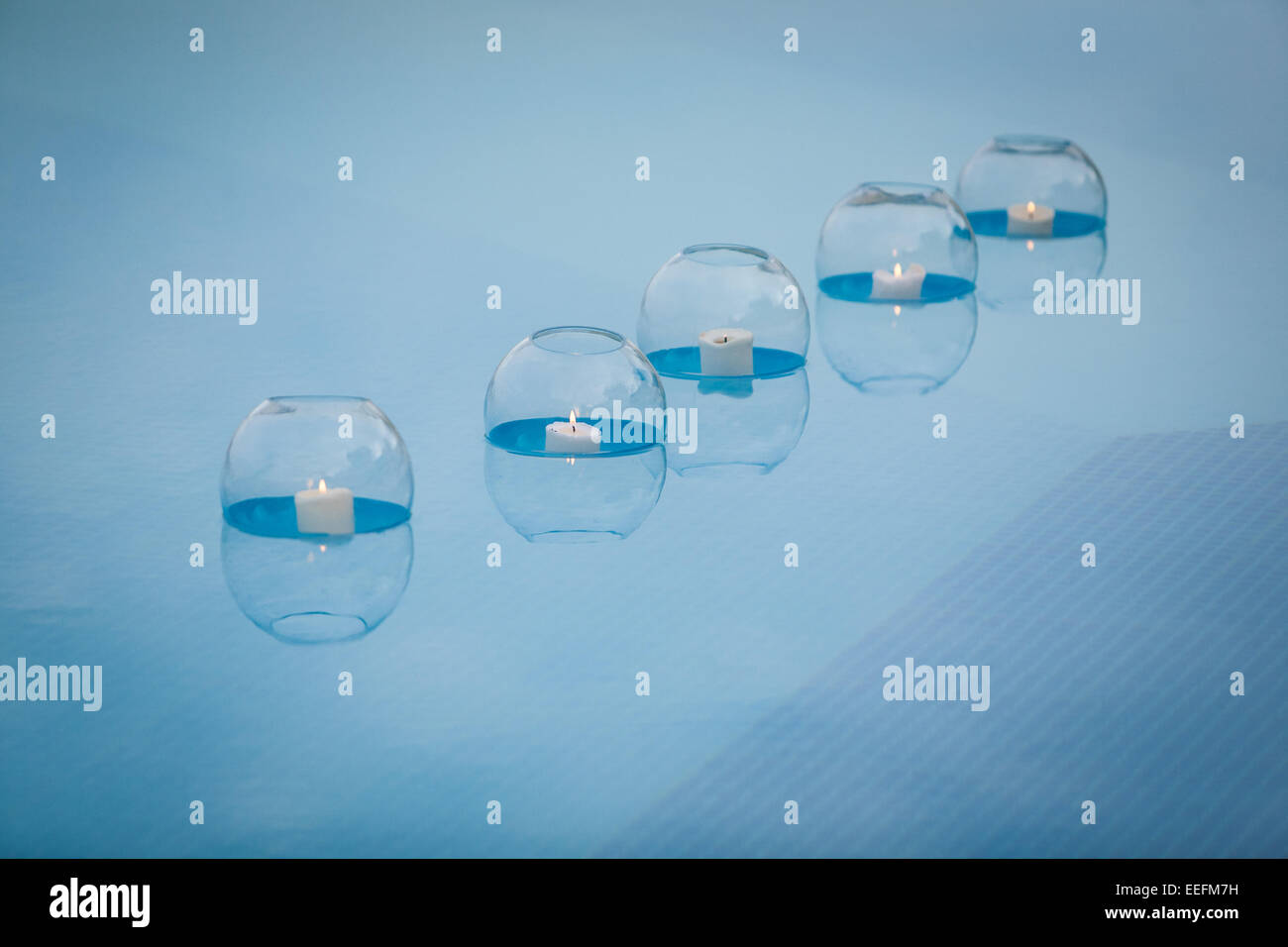 Candles in glass bowls floating in swimming pool Stock Photo Alamy