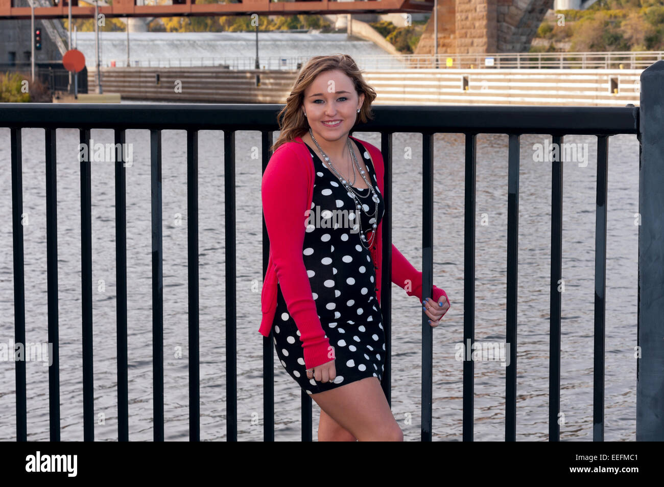 young adult female smiling for portrait in minneapolis leaning against railing along mississippi river Stock Photo