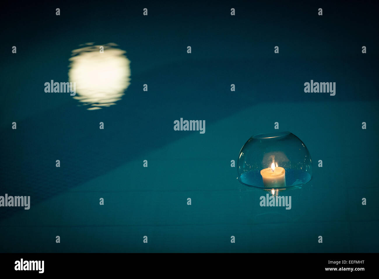 Candles in glass bowls floating in swimming pool Stock Photo Alamy