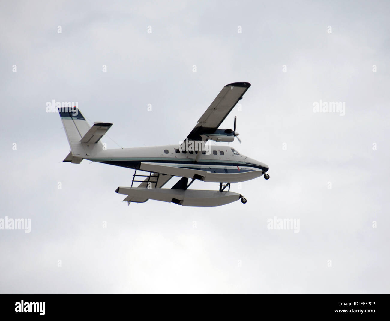 Modern seaplane in flight against cloudy sky Stock Photo