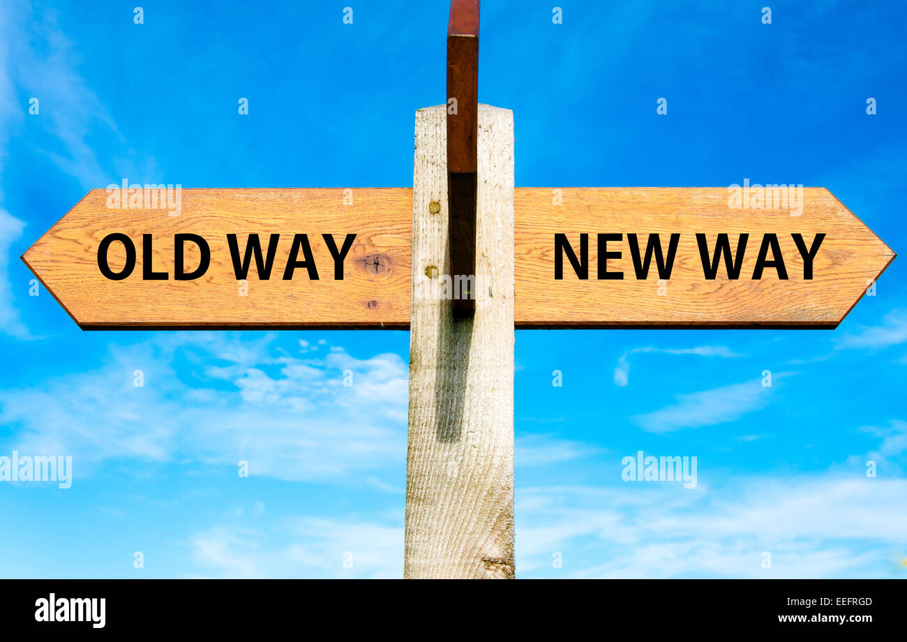 Wooden signpost with two opposite arrows over clear blue sky, Old Way and New Way signs Stock Photo
