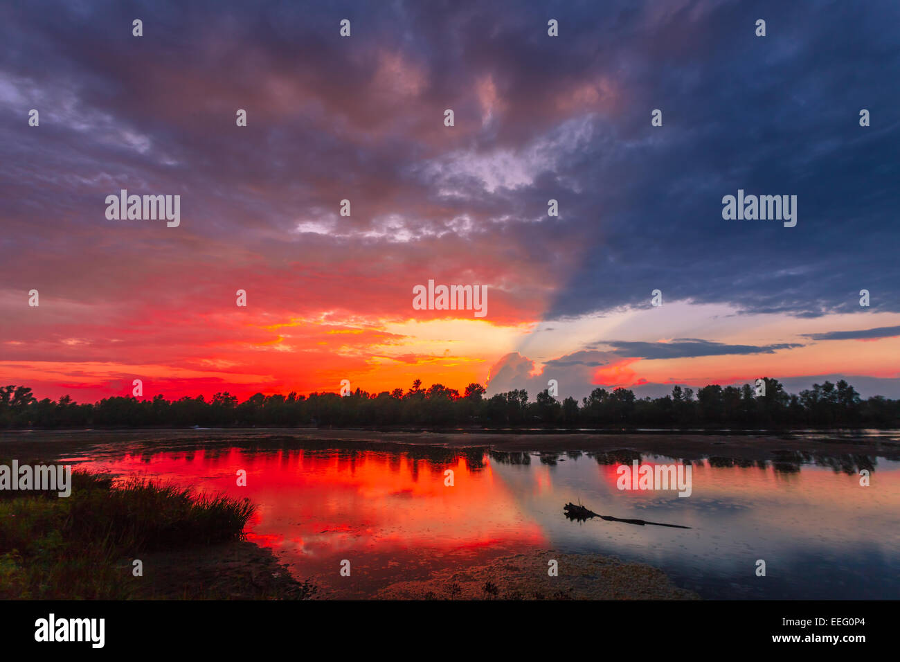 Amazingly colorful sunset with reflective red sand and bright clouds Stock Photo