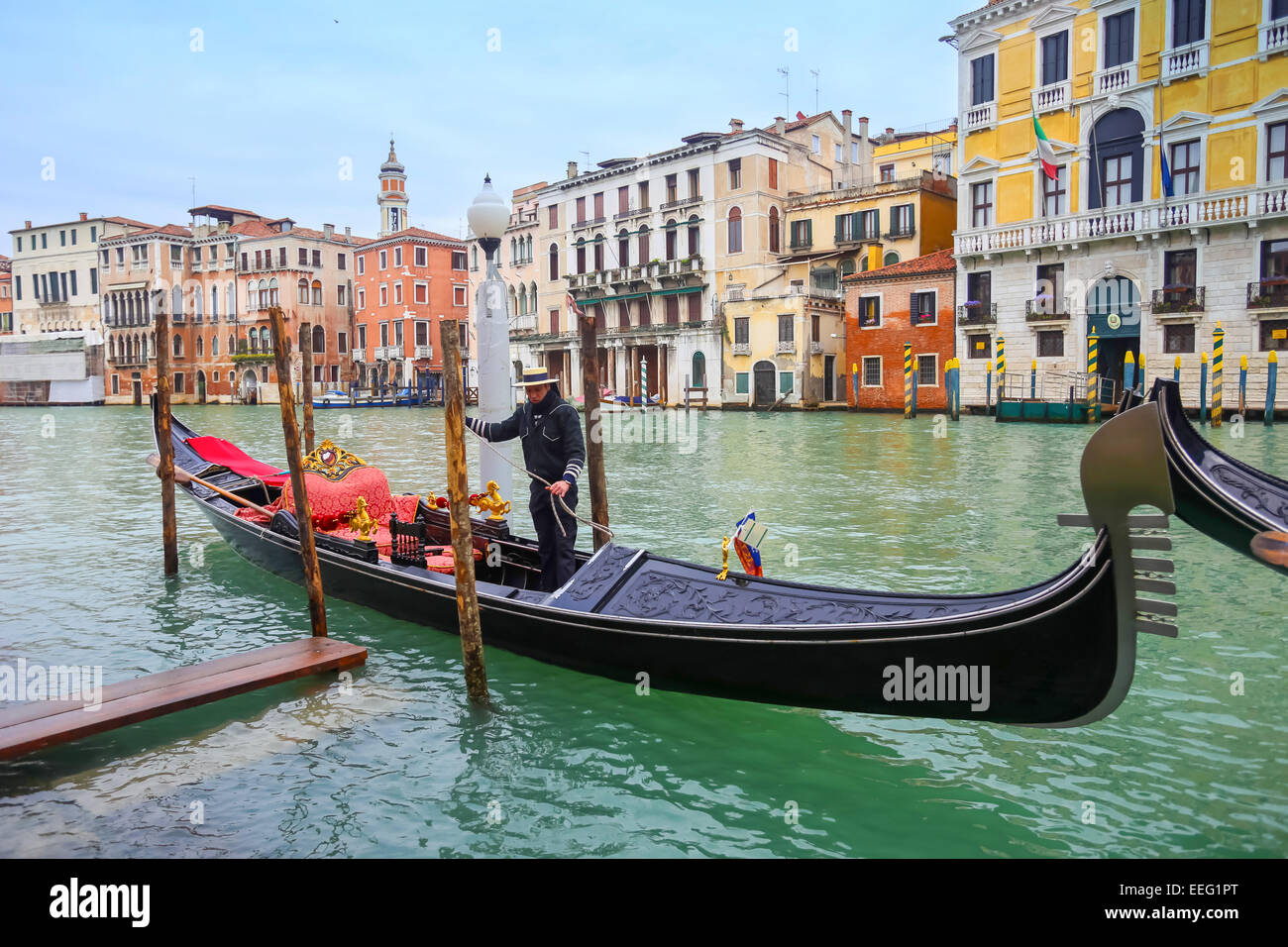 A view of a gondola with gondolier parked in a Campo Erberia square on grand canal in Venice, Italy. Stock Photo