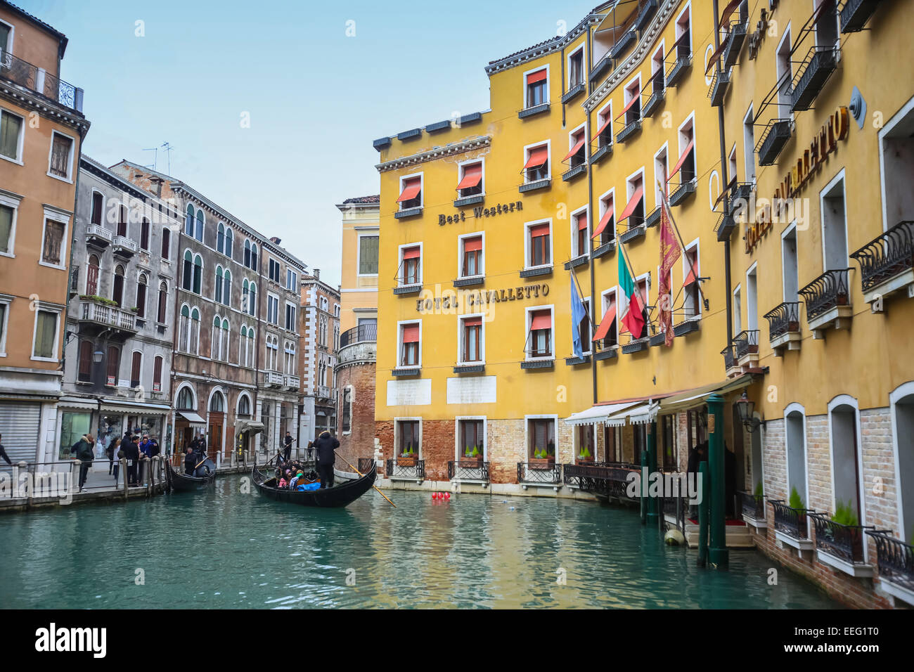 Tourists  sightseeing and sailing in a gondola through a water canal next to Hotel Cavalletto in Venice, Italy. Stock Photo