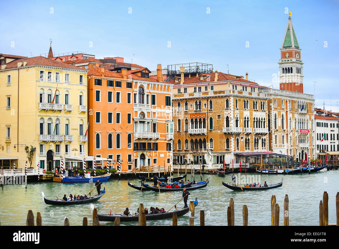 Gondolas with tourists sailing through a grand canal with a view of the St Mark's Campanile bell tower in Venice, Italy. Stock Photo