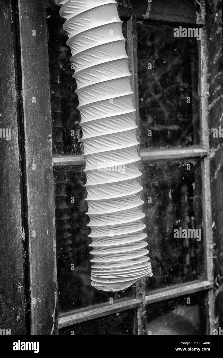 Vent pipe from a tumble dryer, hanging out of a window Stock Photo