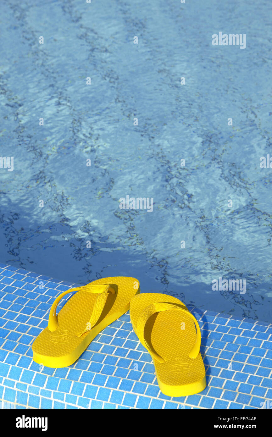 Aussen Pool Schuhe Badeschuhe Flip-Flops Farbe Gelb Poolrand Wasser Blau Sommer Urlaub Freizeit Holiday Swimmingpool Konzepte St Stock Photo
