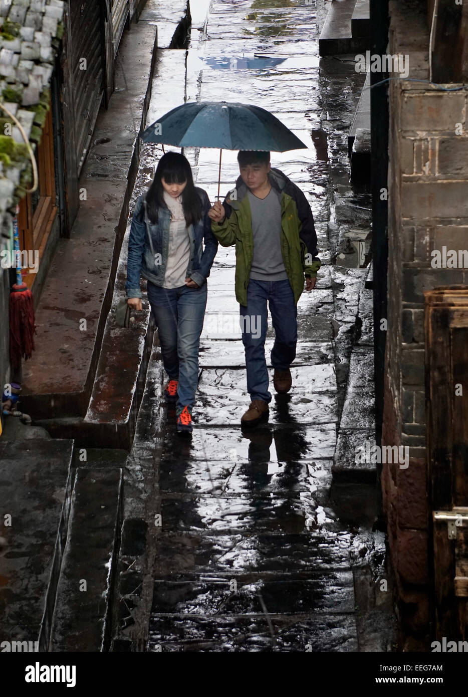 People walking with umbrella in the rain, stone sidewalk, wet, reflection. Stock Photo