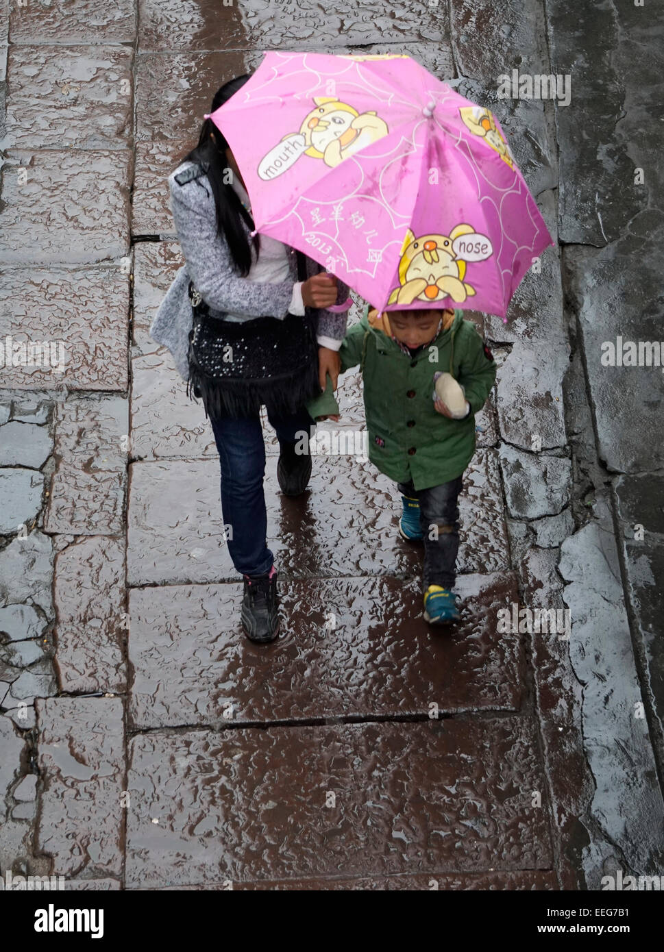 People walking with umbrella in the rain, stone sidewalk, wet, reflection. Stock Photo