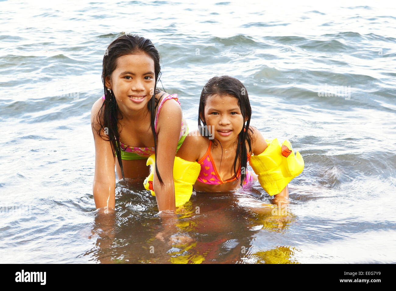2 Asian little ladies posing inside the water with a smile of joy on their faces Stock Photo
