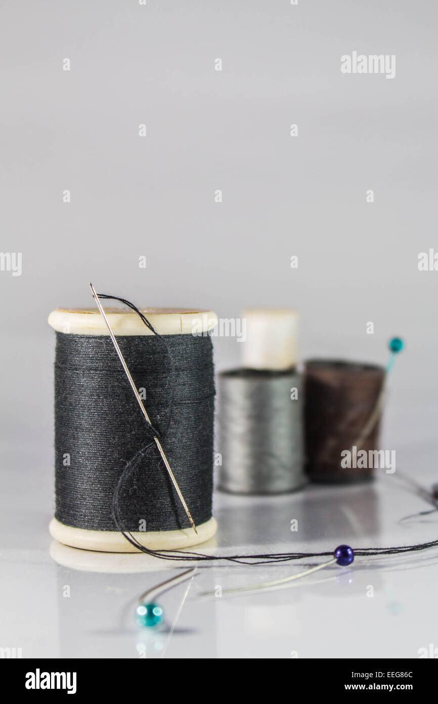 Roll of black thread with a needle inserted Stock Photo Alamy