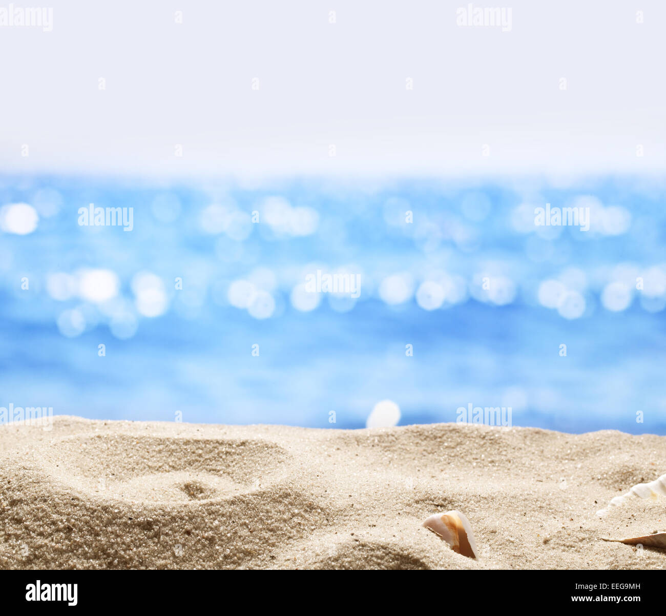 Sand with blurred sea background. File has clipping path for holes in the sand. You can insert the bottle or glass. Stock Photo