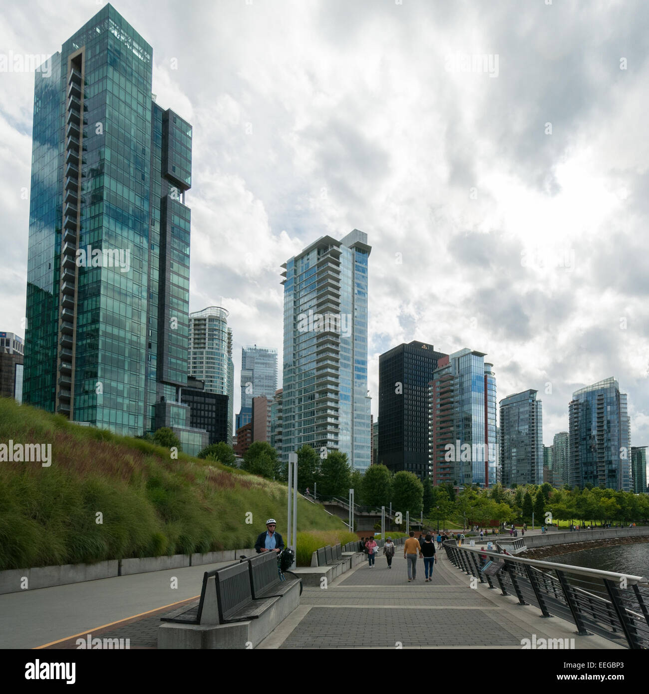 People walking along coal harbor waterfront promenade in front of luxury modern condominiums, downtown Vancouver Stock Photo