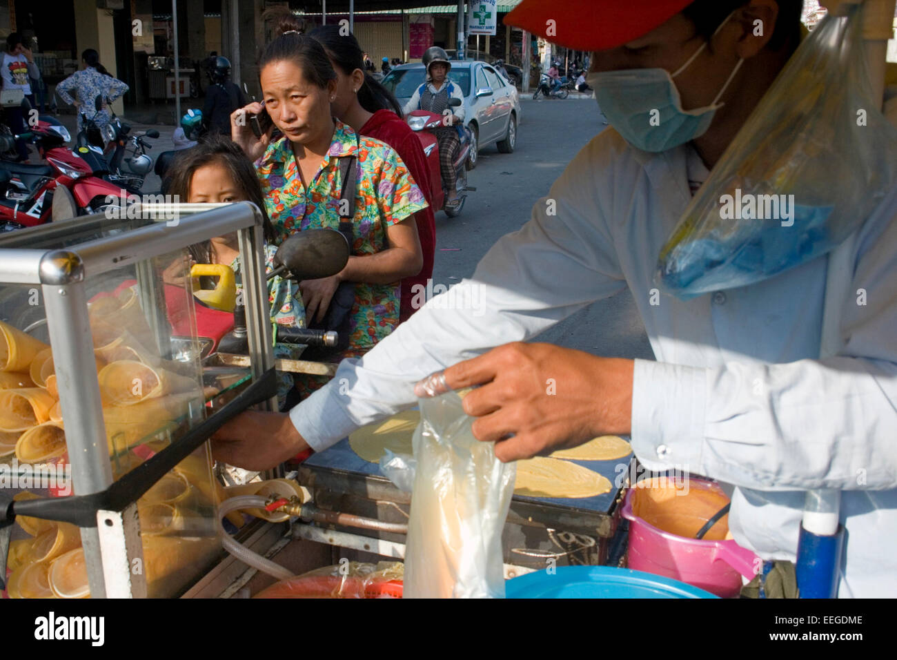 A man is making roti, a popular street food in southeast Asia, on a mobile food cart on a city street in Kampong Cham, Cambodia. Stock Photo