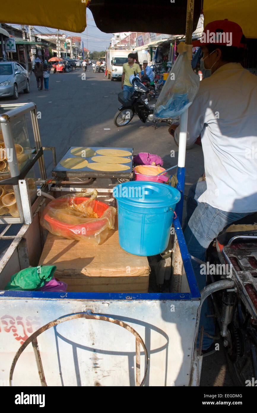 A man is making roti, a popular street food in southeast Asia, on a mobile food cart on a city street in Kampong Cham, Cambodia. Stock Photo