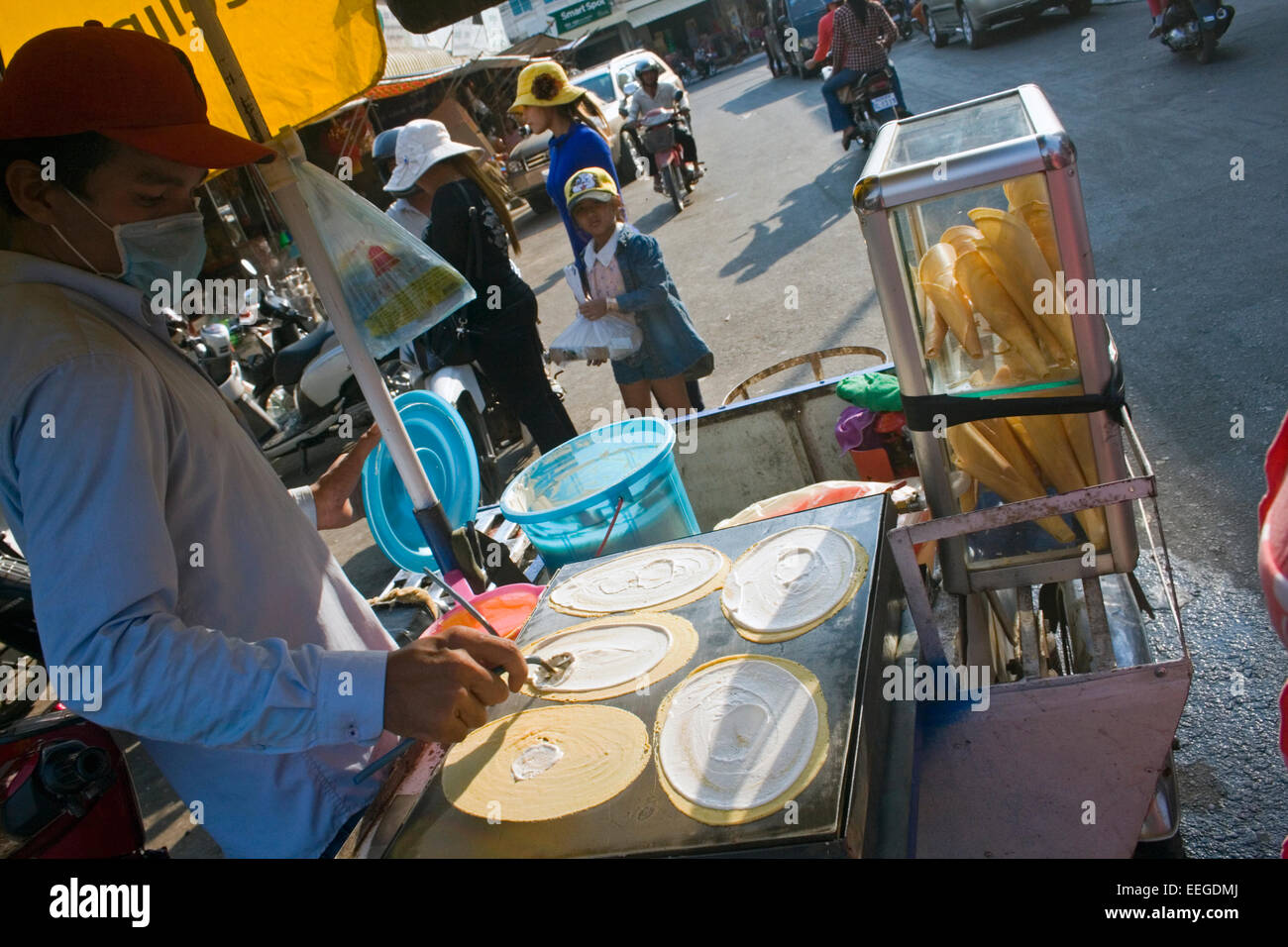 A man is making roti, a popular street food in southeast Asia, on a mobile food cart on a city street in Kampong Cham, Cambodia. Stock Photo