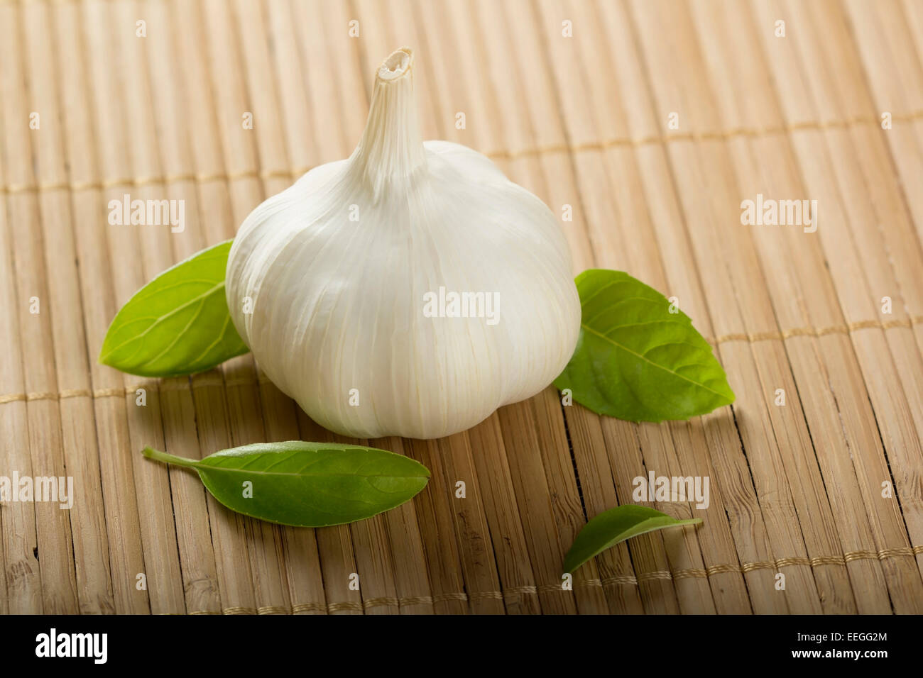 Garlic on a bamboo rug and basil leaves Stock Photo