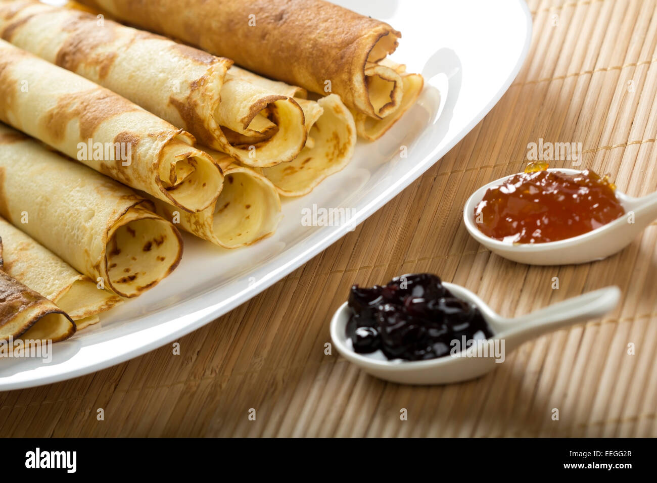 Rolled pancakes with orange jam and black cherry jam Stock Photo