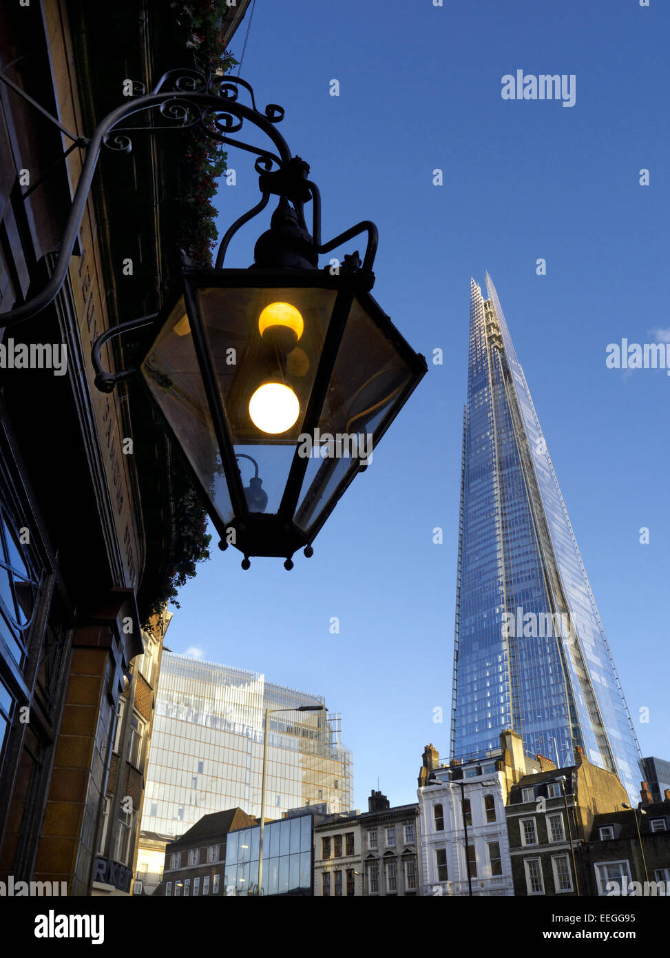 The London Shard building towering over Victorian and Georgian terraced houses, ornate public house lamp in foreground London UK Stock Photo