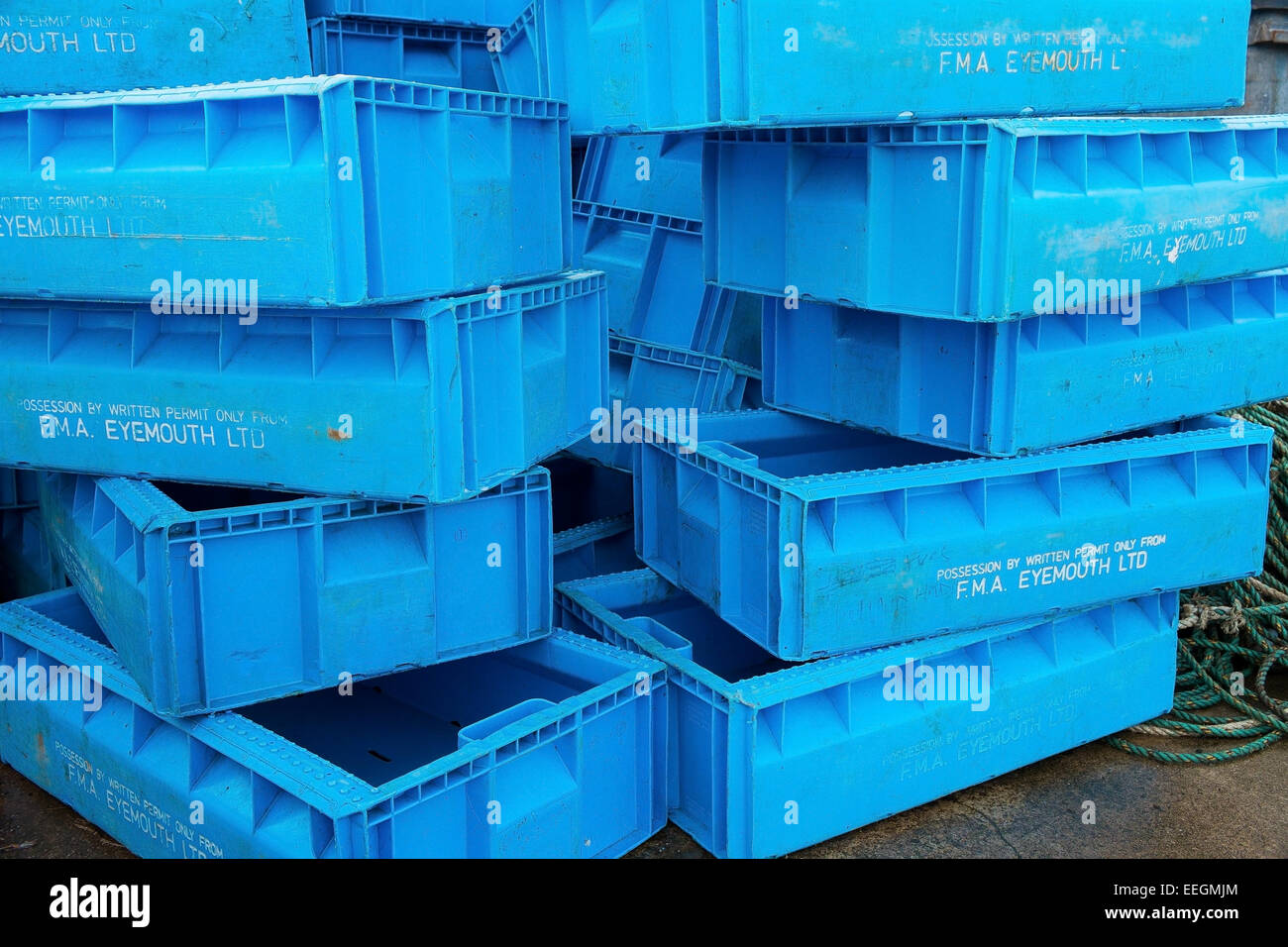 Blue plastic fish boxes stacked up at the harbour of a fishing