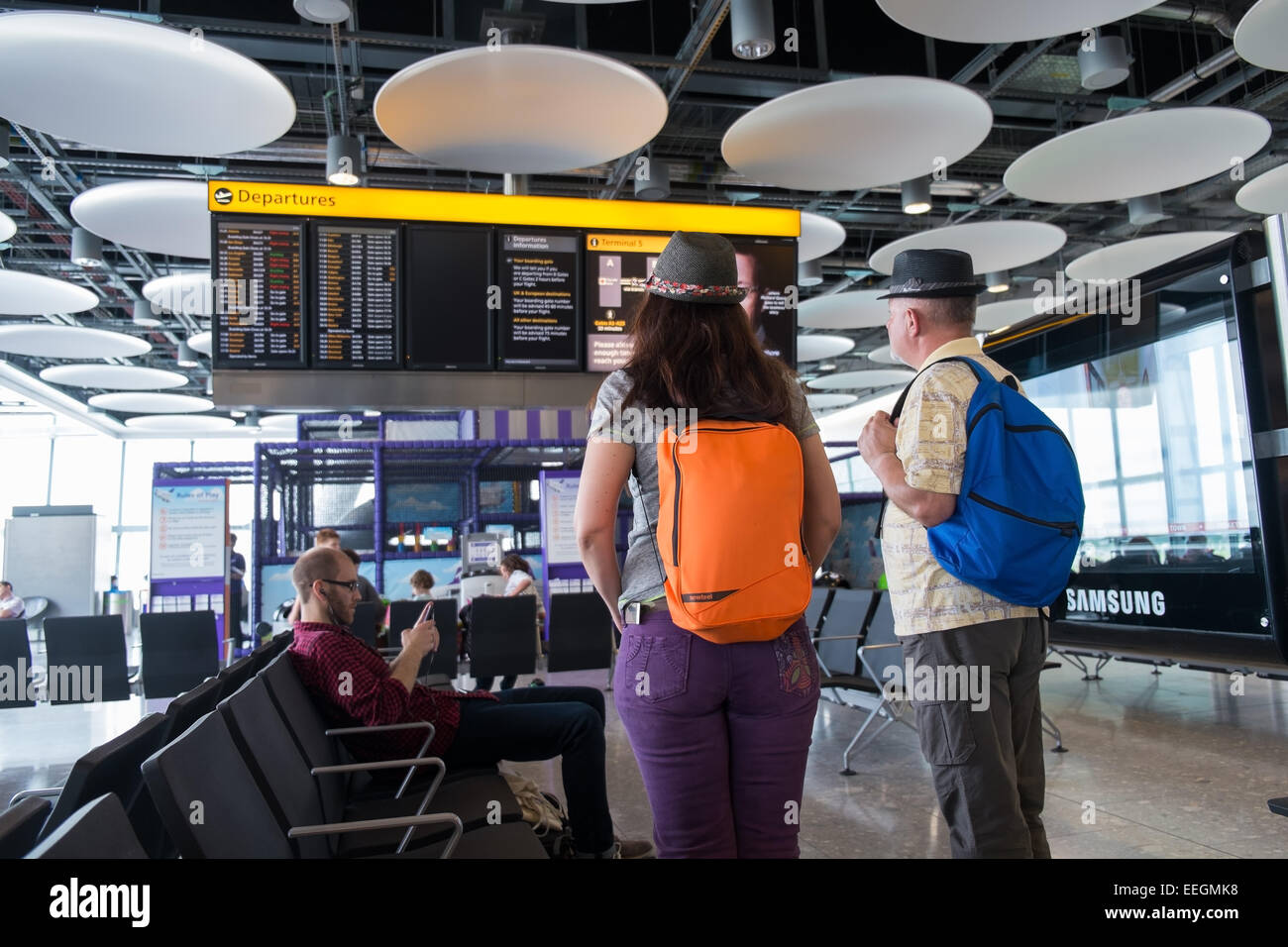 Air passengers watching the departure board at Heathrow, Terminal 5, London. Stock Photo