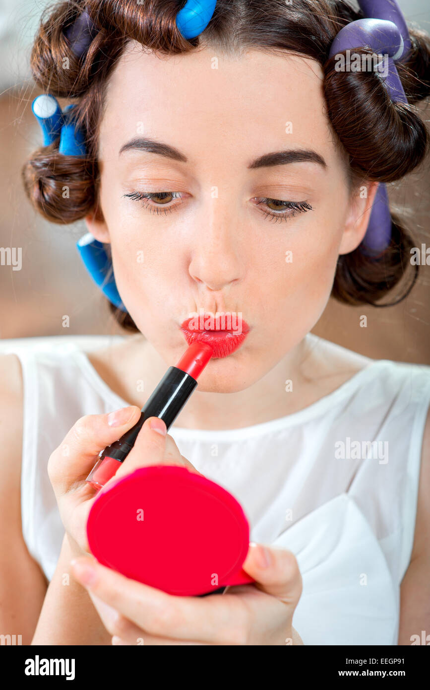 Smiling woman with hair curlers using red lipstick Stock Photo