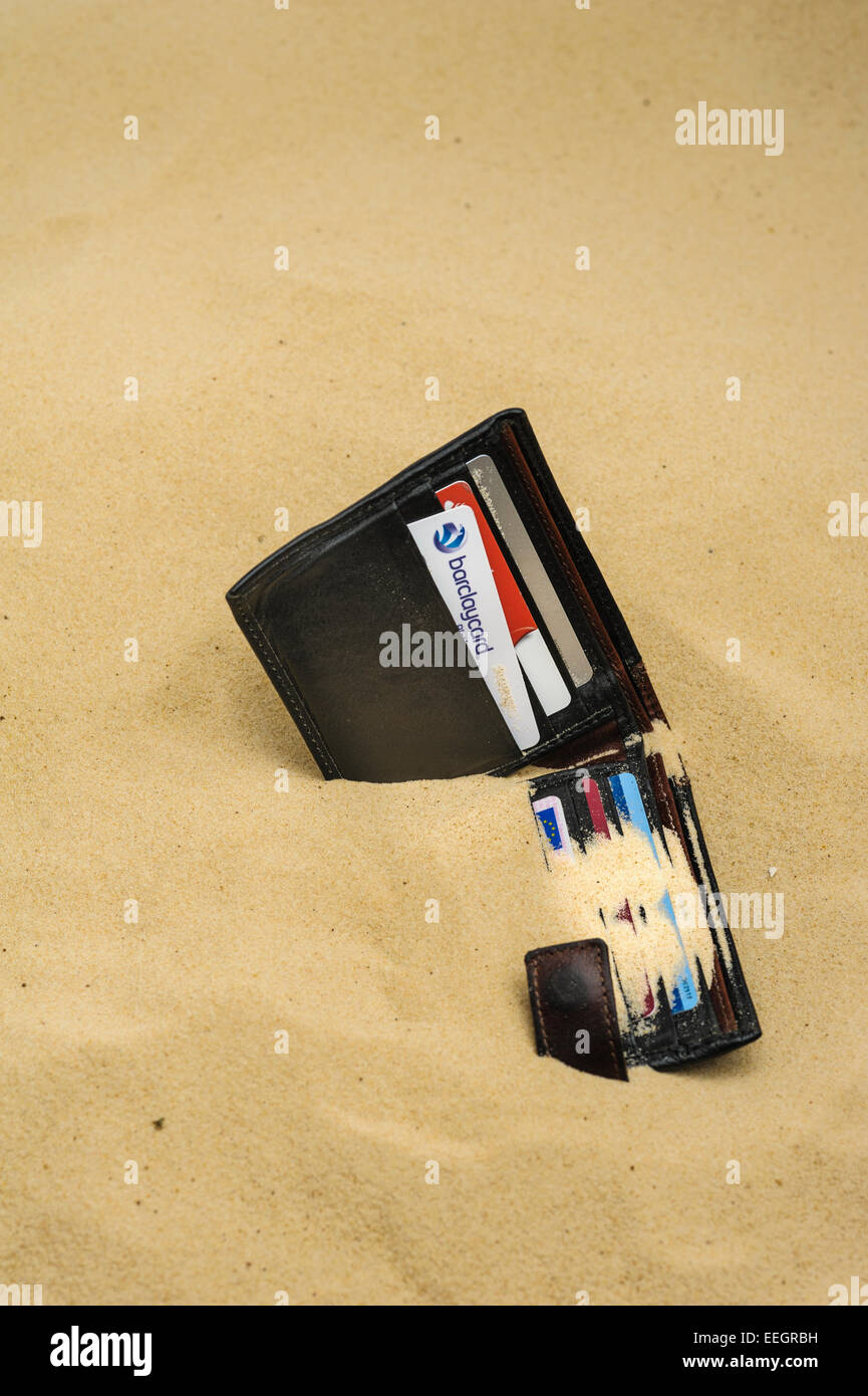 Wallet dropped and half buried on a sandy beach. Stock Photo