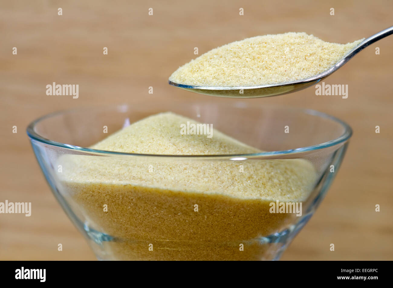 Heaped spoonful of semolina over bowl Stock Photo